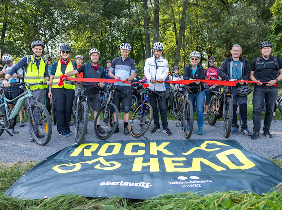 Gruppe von Leuten steht mit Fahrrädern vor Banner