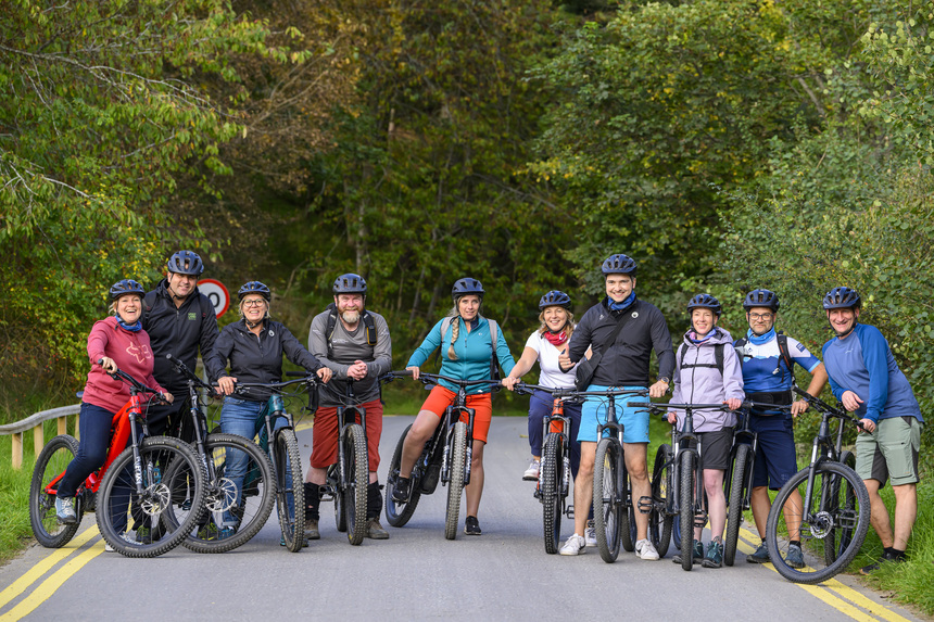 Eine Gruppe von Menschen, die auf einer Straße mit Mountainbikes ein Gruppenbild machen